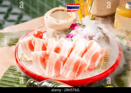 Affettato di maiale crudo e striato in un piatto bianco per lo Yakiniku, il Sukiyaki, il barbecue e lo Shabu. Foto Stock