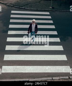 Albino con una macchina fotografica in mano che attraversa la strada Foto Stock