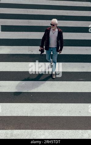 Albino con una macchina fotografica in mano che attraversa la strada Foto Stock