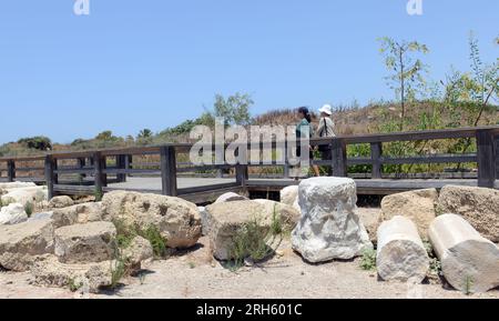 Passeggiata turistica tra le rovine romane nell'antica città scavata di Cesarea in Israele. Foto Stock