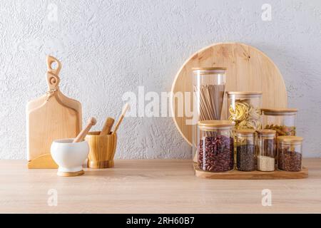 utensili ecologici sul ripiano in legno della cucina contro una parete grigia. vasetti per la conservazione di prodotti sfusi. cucina moderna Foto Stock