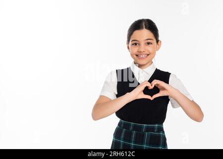 una studentessa felice con un giubbotto nero che mostra il segno del cuore con le mani e guarda la fotocamera isolata su bianco Foto Stock