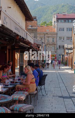 Strada pittoresca con persone sedute in bar/ristoranti nella città di Sarajevo, Bosnia ed Erzegovina, 14 agosto 2023. Foto Stock