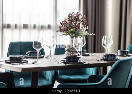 Sala da pranzo con tavolo in legno e pavimento con sedie blu in un appartamento moderno. Ambiente moderno nella zona pranzo dell'appartamento. Foto Stock