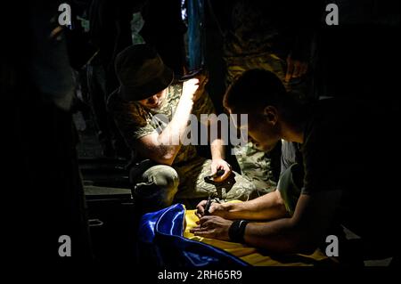 UCRAINA - 11 AGOSTO 2023 - il personale militare firma una bandiera Ucraina come unità di artiglieria della 128th Mountain Assault Brigade serve nello Zaporiz Foto Stock