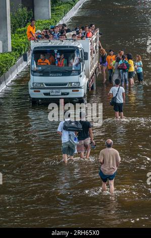 I rifugiati thailandesi attraversano le acque alluvionali per salire su un camion sovraccaricato durante l'alluvione, all'aeroporto internazionale Don Mueang, Bangkok, Thailandia. © Kraig Lieb Foto Stock