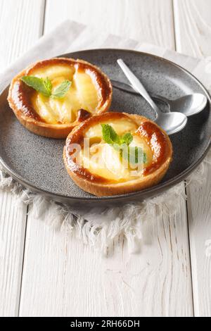 Mini crostate di torta di mele fresche fatte in casa con primi piani di menta in un piatto sul tavolo. Verticale Foto Stock