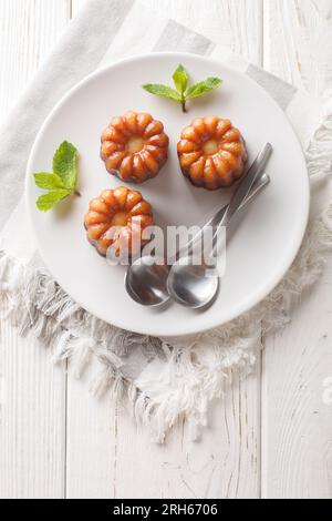 Caneles de bordeaux dessert dolce francese tradizionale da vicino in un piatto sul tavolo. Vista dall'alto verticale Foto Stock