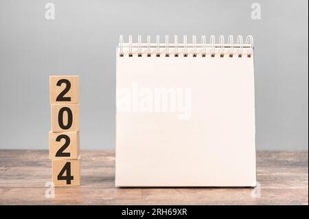 2024 e' il momento di un nuovo inizio. Pianificare le parole e 2024 cubi con sfondo di legno. Anno nuovo. piani per il 2022, spazio vuoto per testo su blocco note, calendario mockup Foto Stock
