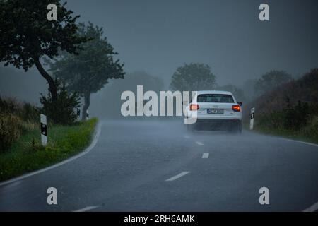 Ein Auto auf einer Landstrasse bei starkem Regen. Foto Stock