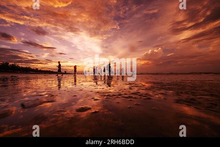 (230814) -- DONGXING, 14 agosto 2023 (Xinhua) -- i turisti si divertono all'alba sulla spiaggia di Jintan a Dongxing, nella regione autonoma di Guangxi Zhuang nel sud della Cina, 14 agosto 2023. La spiaggia di Jintan, situata nella parte meridionale dell'isola di Wanwei, ha una costa di 15 chilometri e prende il nome dal suo colore di sabbia dorata. (Xinhua/Fei Maohua) Foto Stock