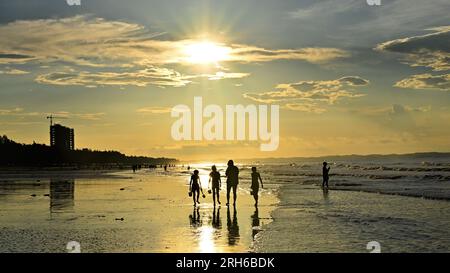 (230814) -- DONGXING, 14 agosto 2023 (Xinhua) -- i turisti si divertono all'alba sulla spiaggia di Jintan a Dongxing, nella regione autonoma di Guangxi Zhuang nel sud della Cina, 14 agosto 2023. La spiaggia di Jintan, situata nella parte meridionale dell'isola di Wanwei, ha una costa di 15 chilometri e prende il nome dal suo colore di sabbia dorata. (Xinhua/Zhang Ailin) Foto Stock