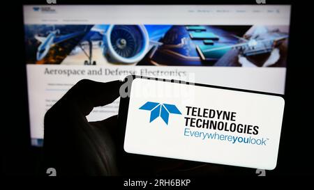 Persona che possiede il cellulare con il logo della società americana Teledyne Technologies incorporato sullo schermo davanti alla pagina Web. Concentrarsi sul display del telefono. Foto Stock