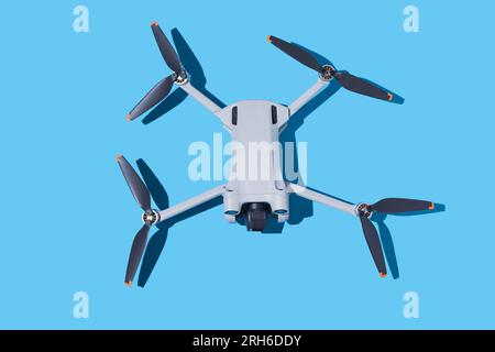 Drone grigio, con fotocamera e videocamera ed eliche scure su sfondo blu. UAV, volare, spia, altitudine, senza equipaggio, tecnologia e concep futuristico Foto Stock