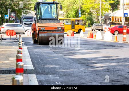 Un potente rullo vibrante per strada compatte l'asfalto fresco in una strada trafficata in una giornata estiva. Copia spazio. Foto Stock