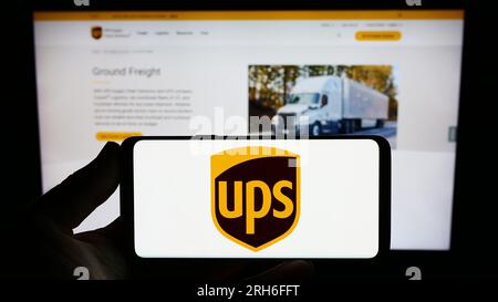 Persona che possiede uno smartphone con il logo della società statunitense United Parcel Service Inc (UPS) sullo schermo davanti al sito Web. Concentrarsi sul display del telefono. Foto Stock