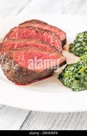 Fianchi la bistecca con gli spinaci cremosi sul piatto Foto Stock