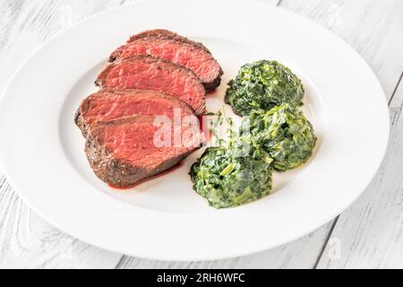 Fianchi la bistecca con gli spinaci cremosi sul piatto Foto Stock