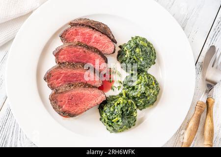 Fianchi la bistecca con gli spinaci cremosi sul piatto Foto Stock