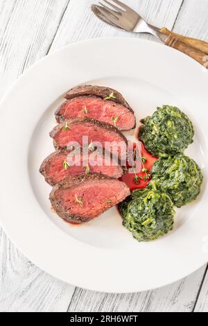 Fianchi la bistecca con gli spinaci cremosi sul piatto Foto Stock