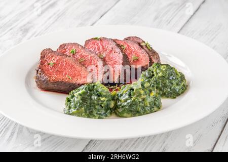 Fianchi la bistecca con gli spinaci cremosi sul piatto Foto Stock