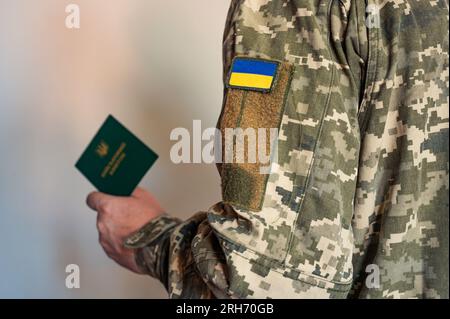 Soldato in tuta tattica tiene in mano un documento di identificazione militare. Uniforme pixel Ucraina Foto Stock