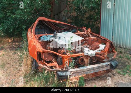 Sul lato della strada c'e' un'auto civile distrutta e bruciata. Guerra in Ucraina. Invasione russa dell'Ucraina. Crimini di guerra Foto Stock