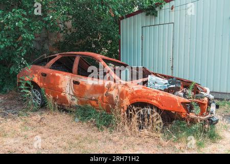 Sul lato della strada c'e' un'auto civile distrutta e bruciata. Guerra in Ucraina. Invasione russa dell'Ucraina. Crimini di guerra Foto Stock