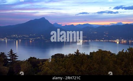 Montagne e alberi con luci da Toscolano Maderno intorno al lago di Garda presi da San Zeno di montagna al crepuscolo d'estate Foto Stock