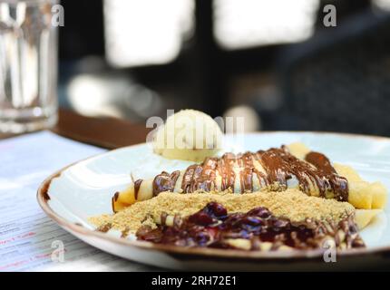 Crepes con crema al cioccolato, spazio copia. Pancake con pasta al cioccolato, nocciole, salsa di ciliegia e una paletta di gelato su un piatto bianco su un ristorante Foto Stock