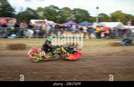 Un pilota di rasaerba da corsa di un team chiamato "The Knight Riders" supera gli spettatori con la BLMRA 500, una falciatrice notturna in stile le Mans di 500 km Foto Stock