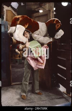 Una foto del 1977 del set di Sesame Street con l'attore Bob McGrath che interpretava Ben Johnson che faceva un volto con un grande cane imbottito sulla testa. In uno studio a Broadway nell'Upper West Side di Manhattan. Foto Stock