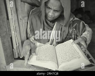 Una donna che legge il corano. Circa 919.000 rifugiati Rohingya vivono nei campi di Kutupalong e Nayapara nella regione del Bazar di Cox, che sono diventati alcuni dei campi più grandi e densamente popolati del mondo. Bangladesh. Foto Stock