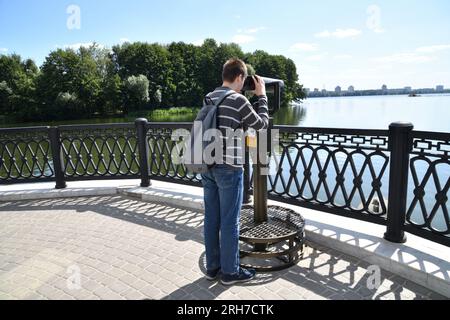 Voronezh, Russia - 23 agosto. 2018. Un adolescente con uno zaino guarda in binocolo sull'Admiralteiskaya Embankment Foto Stock