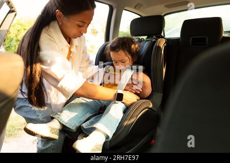 Mamma asiatica seduto bambino figlia in cassaforte sedia in auto Foto Stock