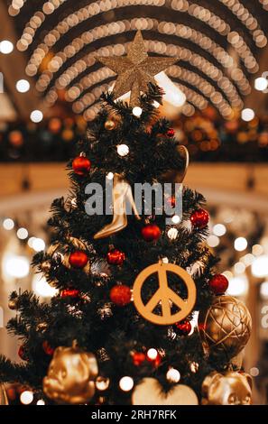 Decorazione di Natale con hippie icona figurine e scarpe alte del tallone femminile appesi su un albero di Natale. Decorazioni creative Foto Stock