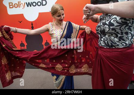 A woman teaches a visitor to the India Day Festival to wear a sari in the Island of Dreams Park in Moscow, Russia Stock Photo