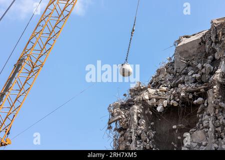 Pesante gru a sfera che demolisce vecchio edificio contro il cielo blu in Germania Magdeburgo. Smantellamento degli edifici e smaltimento dei rifiuti di costruzione Foto Stock