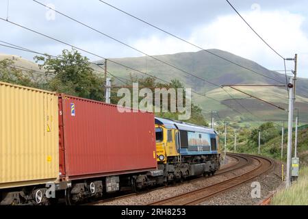 Classe 66 capannone diesel-elettrico loco, numero 66709 chiamato Sorrento, su un convoglio lungo la West Coast Main Line a Lowgill in Cumbria, l'11 agosto 2023. Foto Stock