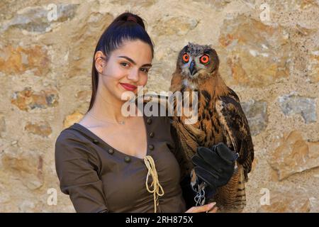 Una falconiera femmina con in mano una giovane aquila eurasiatica con grandi e bellissimi occhi arancioni nella fortezza di Golubac a Golubac, in Serbia Foto Stock