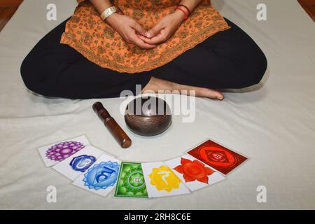 Una donna che pratica meditazione e guarigione con una ciotola tibetana. Corpo umano 7 immagini del sistema energetico Chakras, meditazione yoga. Foto Stock