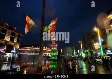 Srinagar, India. 14 agosto 2023. La gente cammina davanti alla torre dell'orologio illuminata con la bandiera nazionale dell'India alla vigilia del giorno dell'indipendenza del paese a Srinagar il 14 agosto 2023. (Foto di Mubashir Hassan/Pacific Press) credito: Pacific Press Media Production Corp./Alamy Live News Foto Stock