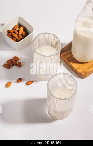 Due bicchieri a coste con latte di mandorla su tavolo bianco. Latte vegano alternativo al latte Foto Stock