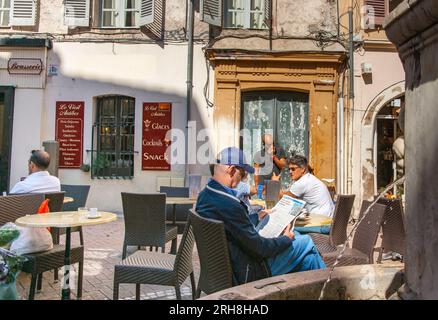 Antibes Francia - 1 maggio 2011; uomini che si rilassano nel cortile del Vieil Antibes con un solo uomo che legge il giornale.1 Foto Stock