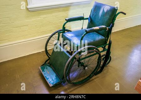 Vecchia sedia a rotelle disabitata Foto Stock