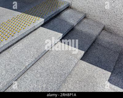 scala in granito con contrassegni gialli antiscivolo per non vedenti. Foto Stock