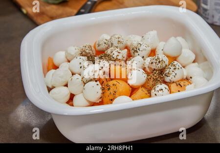 Palle di melone tagliate con cucchiaio speciale e mozzarella in una ciotola in cucina Foto Stock