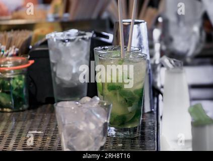 Il barista prepara un cocktail mojito con lime e menta fresca in un ristorante bar di Huntington Beach, Orange County, California, USA Foto Stock