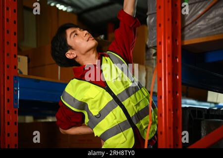 Turbato un lavoratore maschio che soffre di mal di schiena mentre sedeva sulle scale del magazzino. Concetto di lavoratori industriali e industriali Foto Stock