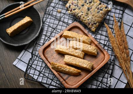 Tempeh crudo a fette su un piatto di legno. Tempeh o Tempe a base di soia fermentata, cibo vegetariano Foto Stock